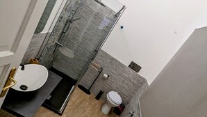 Un baño moderno con cabina de ducha de vidrio, un lavabo blanco y un inodoro.