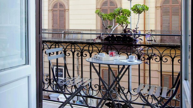Un balcón con una mesa, sillas y plantas en macetas.