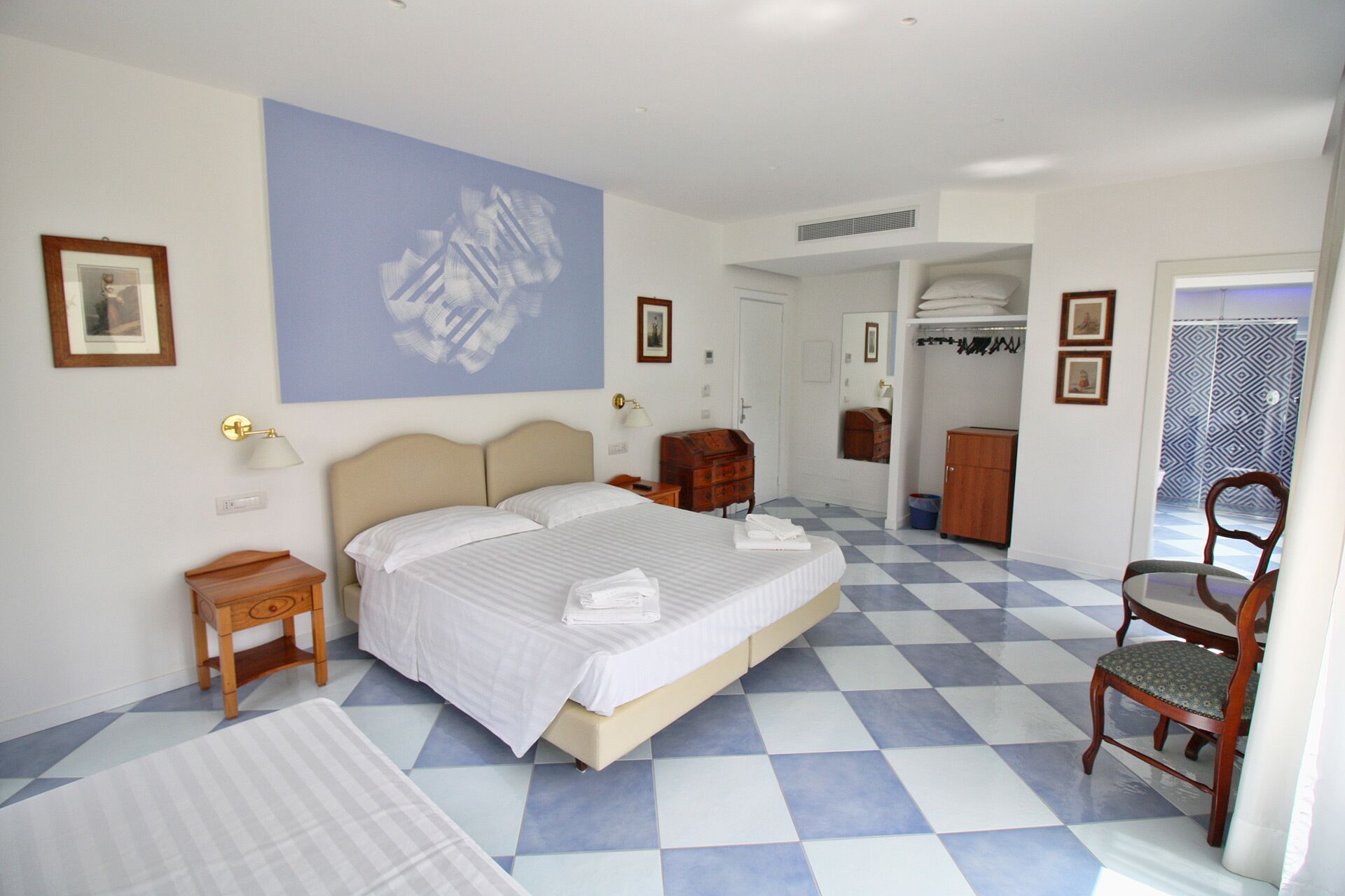 Ein Hotelzimmer mit einem großen Bett, einem Sessel, einem Schminktisch und einem Kleiderschrank.