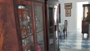 Una habitación con un mueble grande de madera con puertas de vidrio, piso a cuadros y una silla.