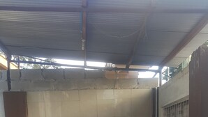 A room with a tiled floor, a white partition wall, a metal-framed chair, and a small white cabinet. - Dar eco backpackers (Dar es Salaam)