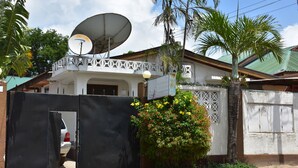 A gated residential area with a satellite dish, a white building with a balcony, and a palm tree. - Dar eco backpackers (Dar es Salaam)