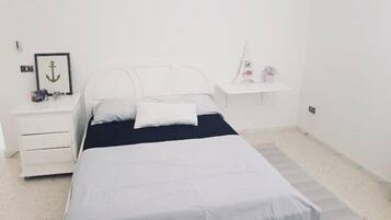 A minimalist bedroom with a bed, a nightstand, and a small shelf.