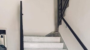 Una escalera con escalones de mármol blanco y barandillas de metal negro.