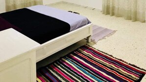 Un dormitorio pequeño y sencillo con una cama individual, una ventana con cortinas y una pared blanca lisa.