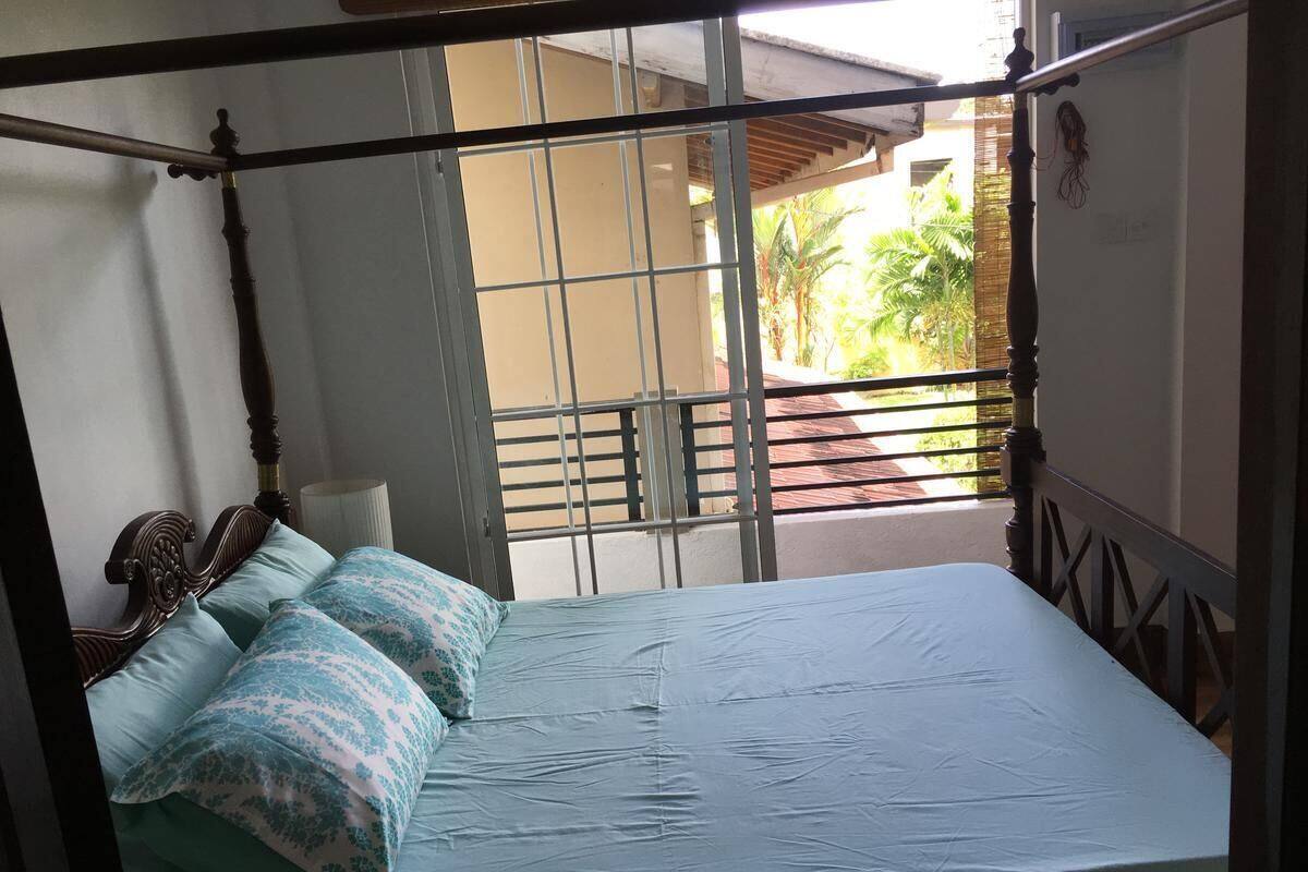 A bed with a metal frame and a view of the outdoors through a window.