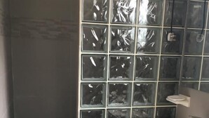 Ein Badezimmer mit modernem Design, das eine große Glasblockwand, ein Standwaschbecken und eine kleine Ablagefläche zeigt.