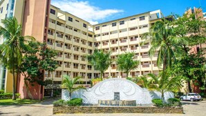 A multi-story hotel with a central courtyard, palm trees, and a decorative entrance. - Chrystal Baharini (Diani Beach)