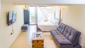 A room with a bed, a sofa, a TV, and a wooden chest. - Chrystal Baharini (Diani Beach)