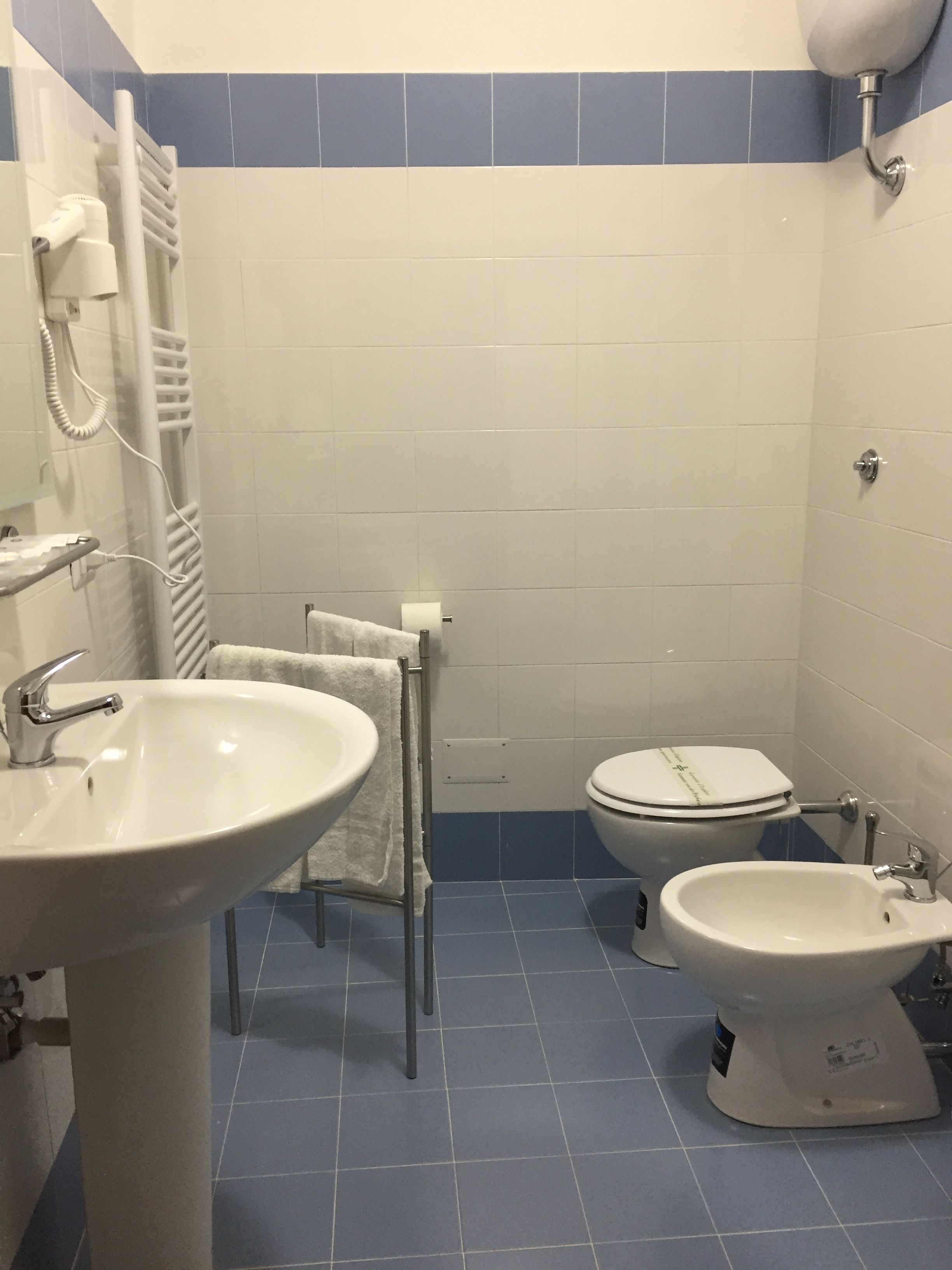 Ein Badezimmer mit Waschbecken, Toilette, Bidet und Handtuchhalter.