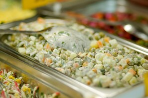 A buffet with various dishes, including a salad with mixed vegetables and a creamy dressing.