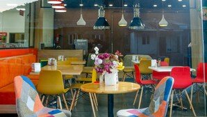 A restaurant interior with colorful chairs, a round table, and pendant lighting. - Hotel Lider Complex (Vayk)