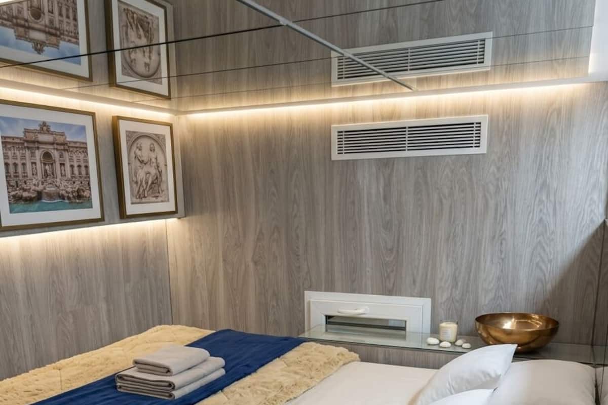 Ein modernes Schlafzimmer mit einem Bett, einem Nachttisch, einem Wandlüfter und gerahmten Bildern.