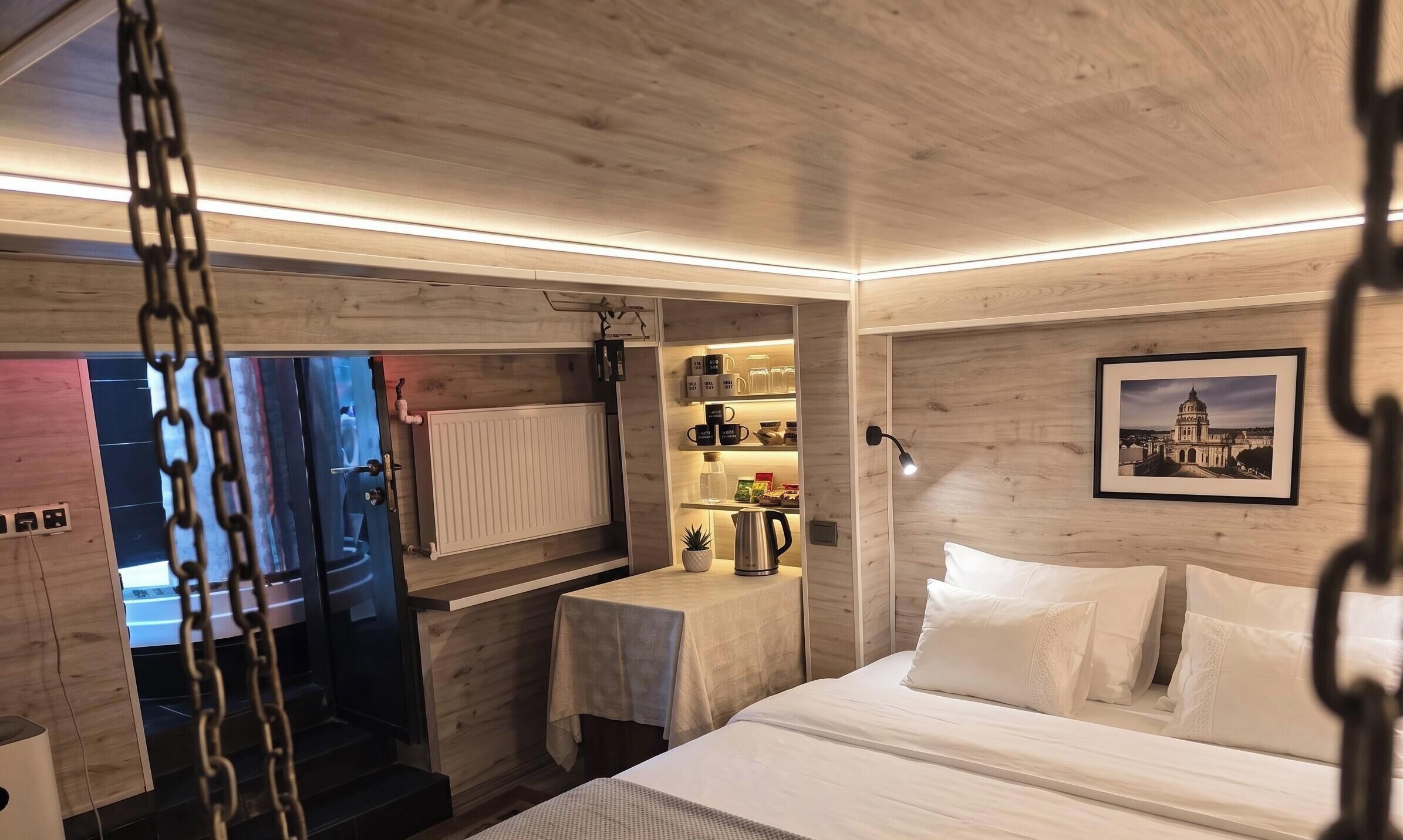 Habitación de hotel moderna con cama, mesita de noche y vistas a un paisaje urbano.