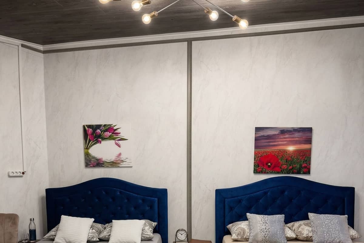 Ein Schlafzimmer mit zwei Betten, einer modernen Chandelierleuchtre und Kunstwerken an den Wänden.