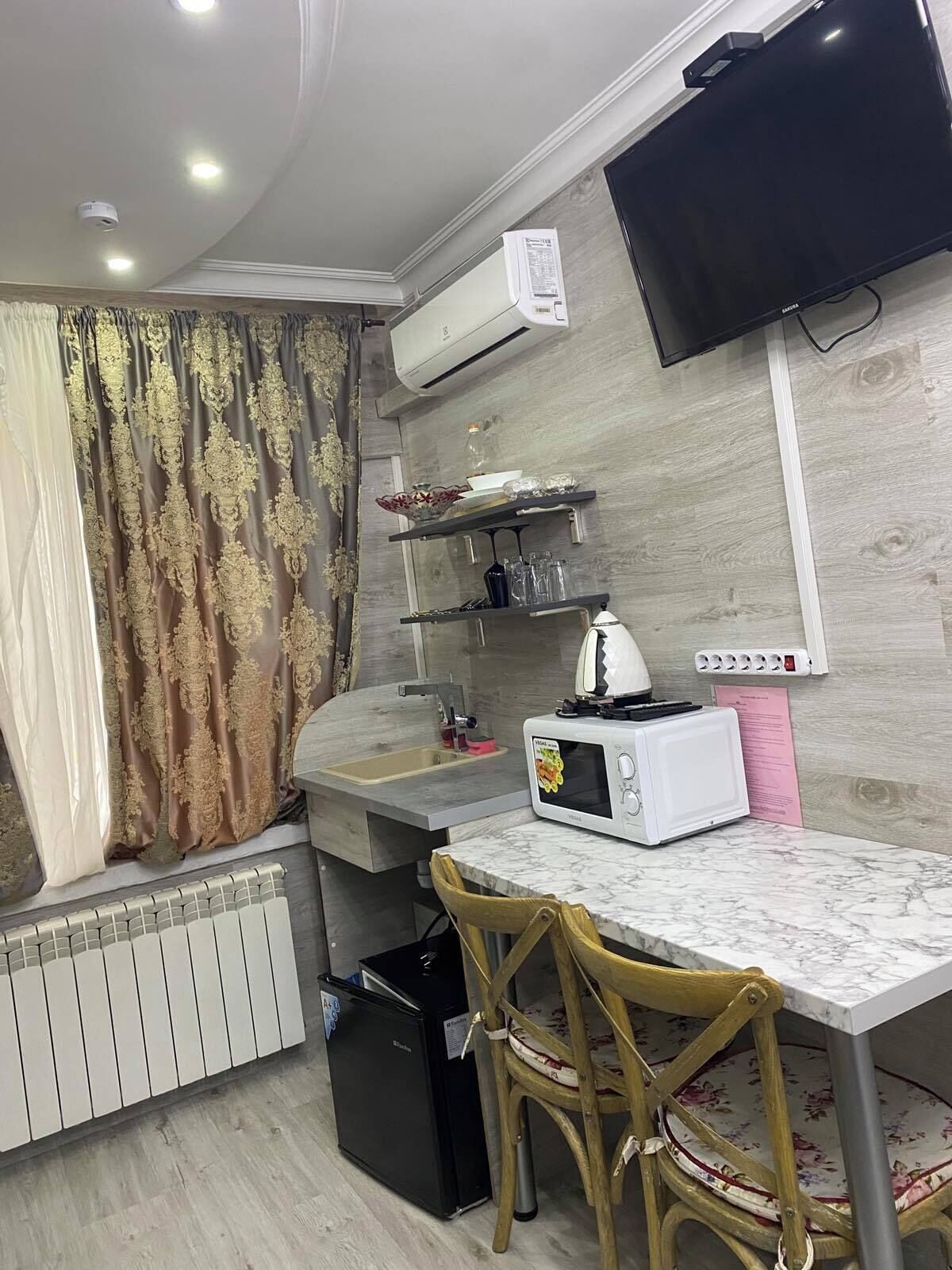 Una cocina compacta con microondas, fregadero y un refrigerador pequeño.