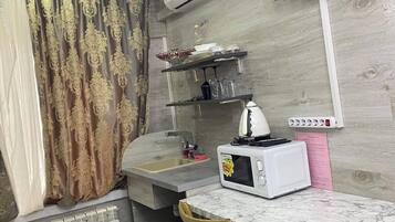 Una cocina compacta con microondas, fregadero y un refrigerador pequeño.