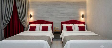 A hotel room with two beds, red and white bedding, a wooden floor, and a wall-mounted light fixture.