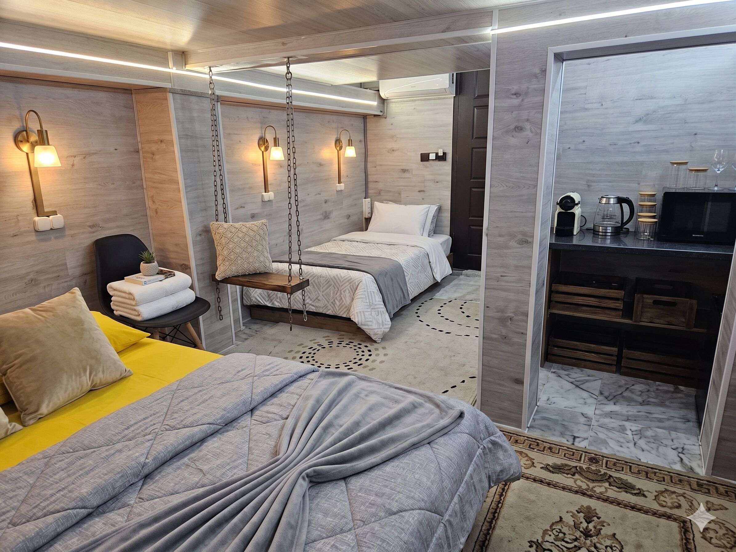 A modern bedroom with a bed, a hanging chair, bedside lamps, and a kitchenette.