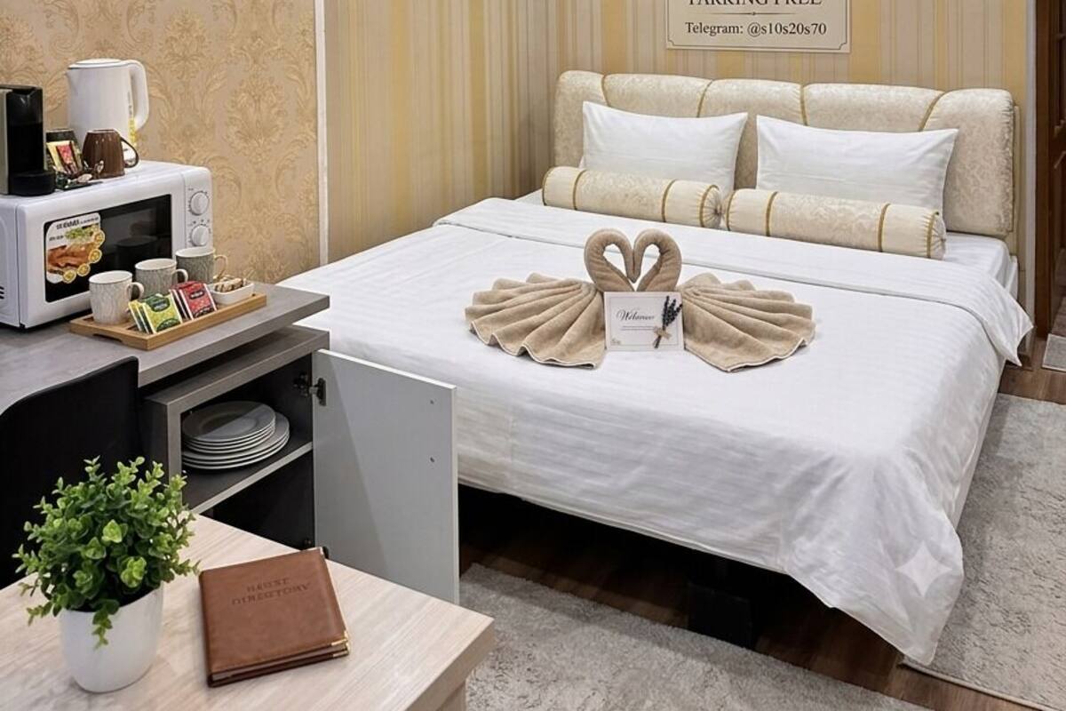 Ein Hotelzimmer mit einem Bett, einem Schreibtisch mit Mikrowelle, einem Telefon und einer kleinen Pflanze.