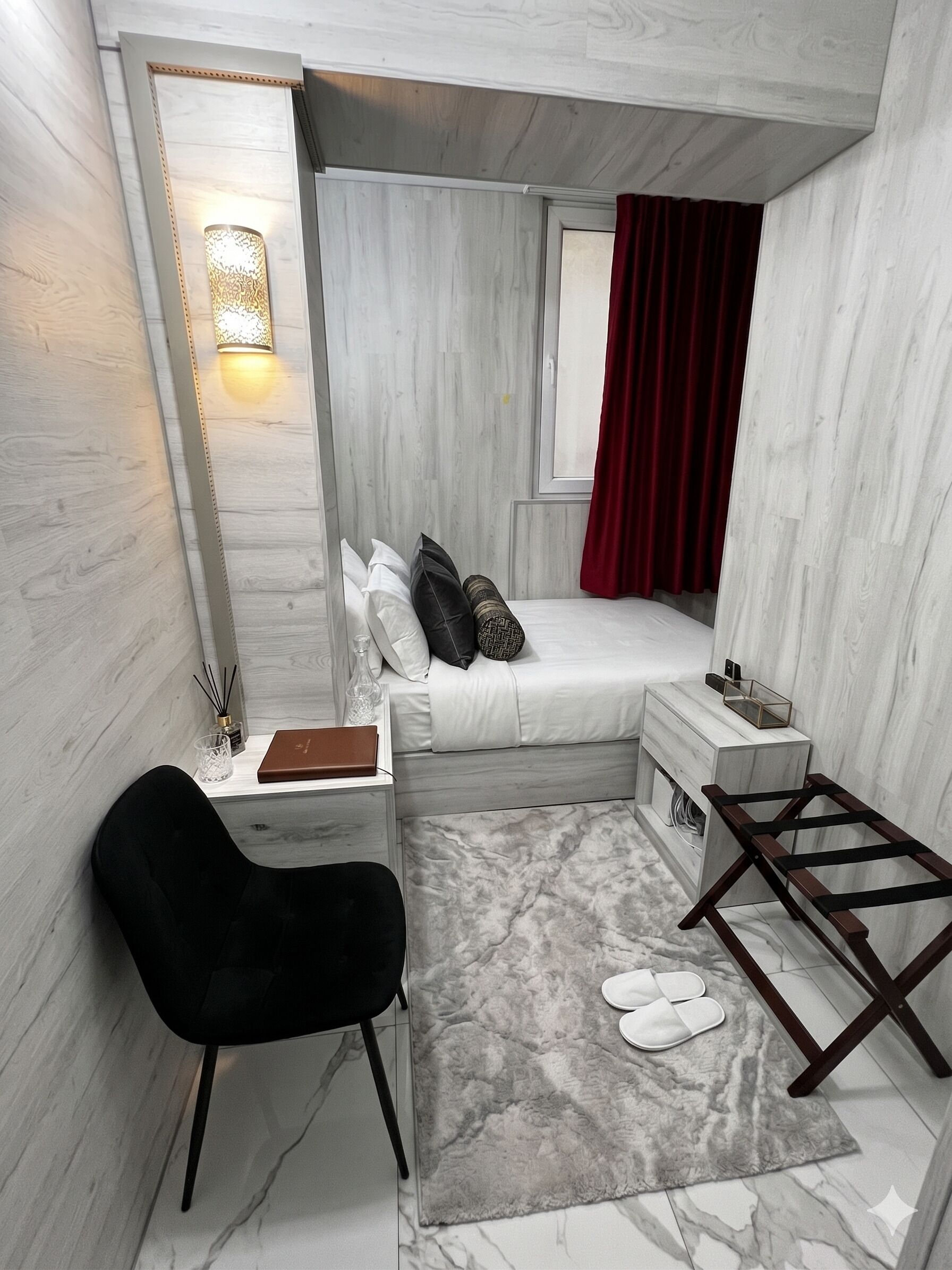 Une chambre à coucher de taille réduite, comprenant un lit, une table de chevet, une chaise et un petit espace bureau.