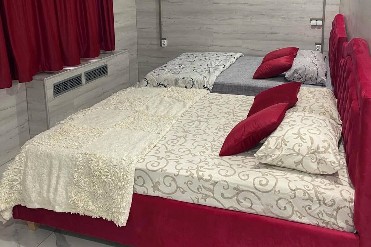 Ein Schlafzimmer mit einem Bett, zwei Kissen, einer Decke und einem roten Vorhang.