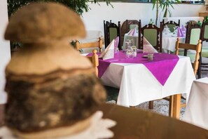 Een eettafel met een witte tafelkleed en een paarse tafelrunner, omringd door houten stoelen.