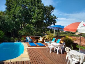 A poolside area with lounge chairs, a wooden deck, and a view of the surrounding greenery. - Mira Playa Geribá (Búzios)