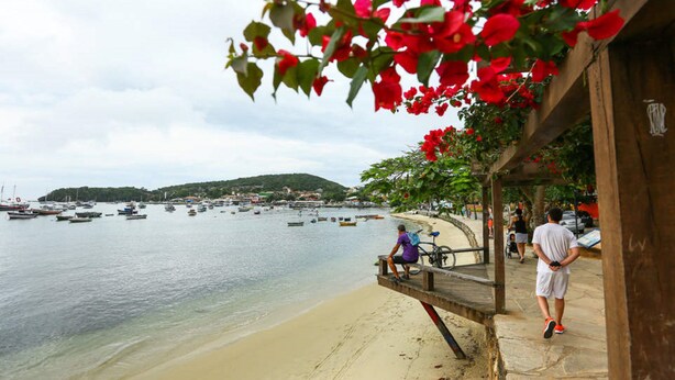 A beach with a wooden pier, boats, and people. - Mira Playa Geribá (Búzios)