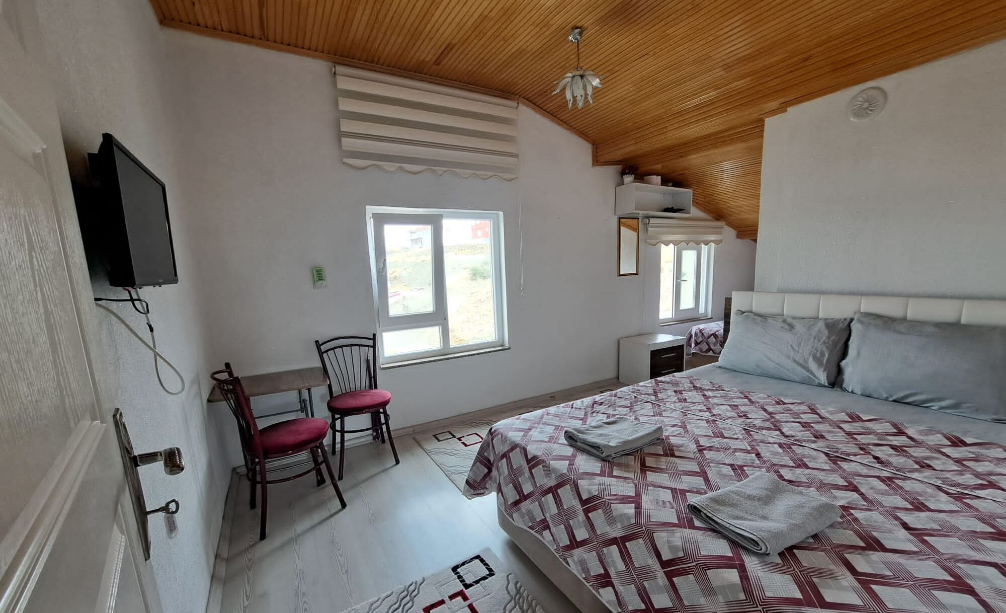 Quarto com cama, cadeira, escrivaninha e televisão.