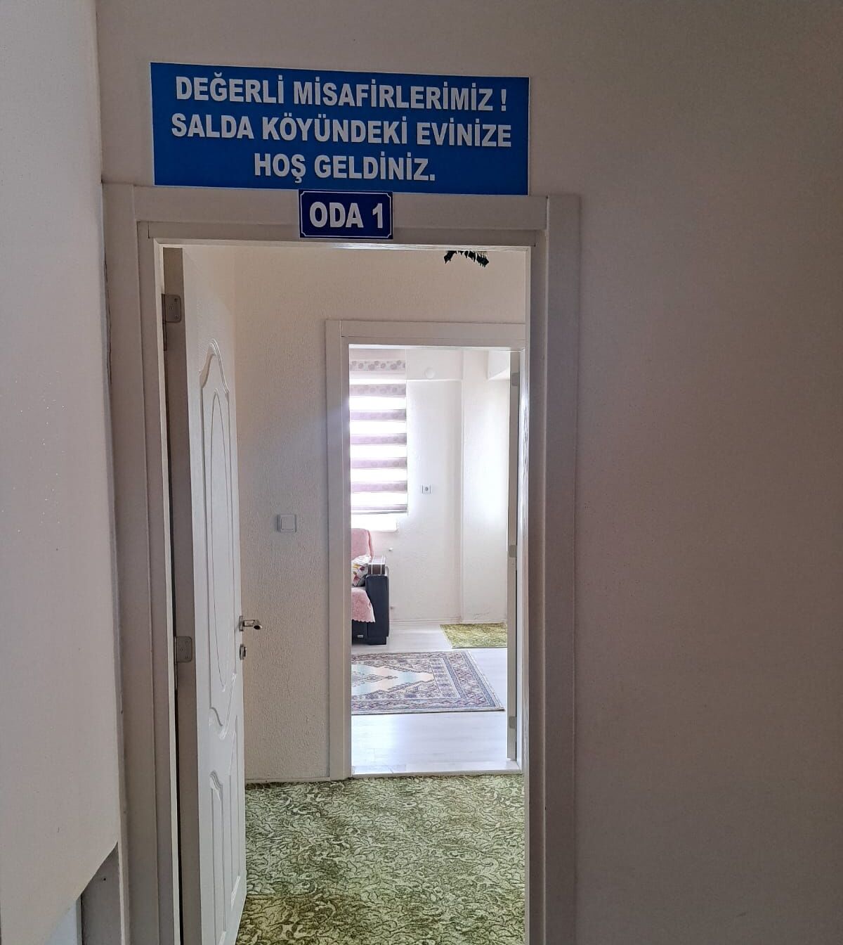 A hallway with a sign indicating a room number and a message in Turkish.