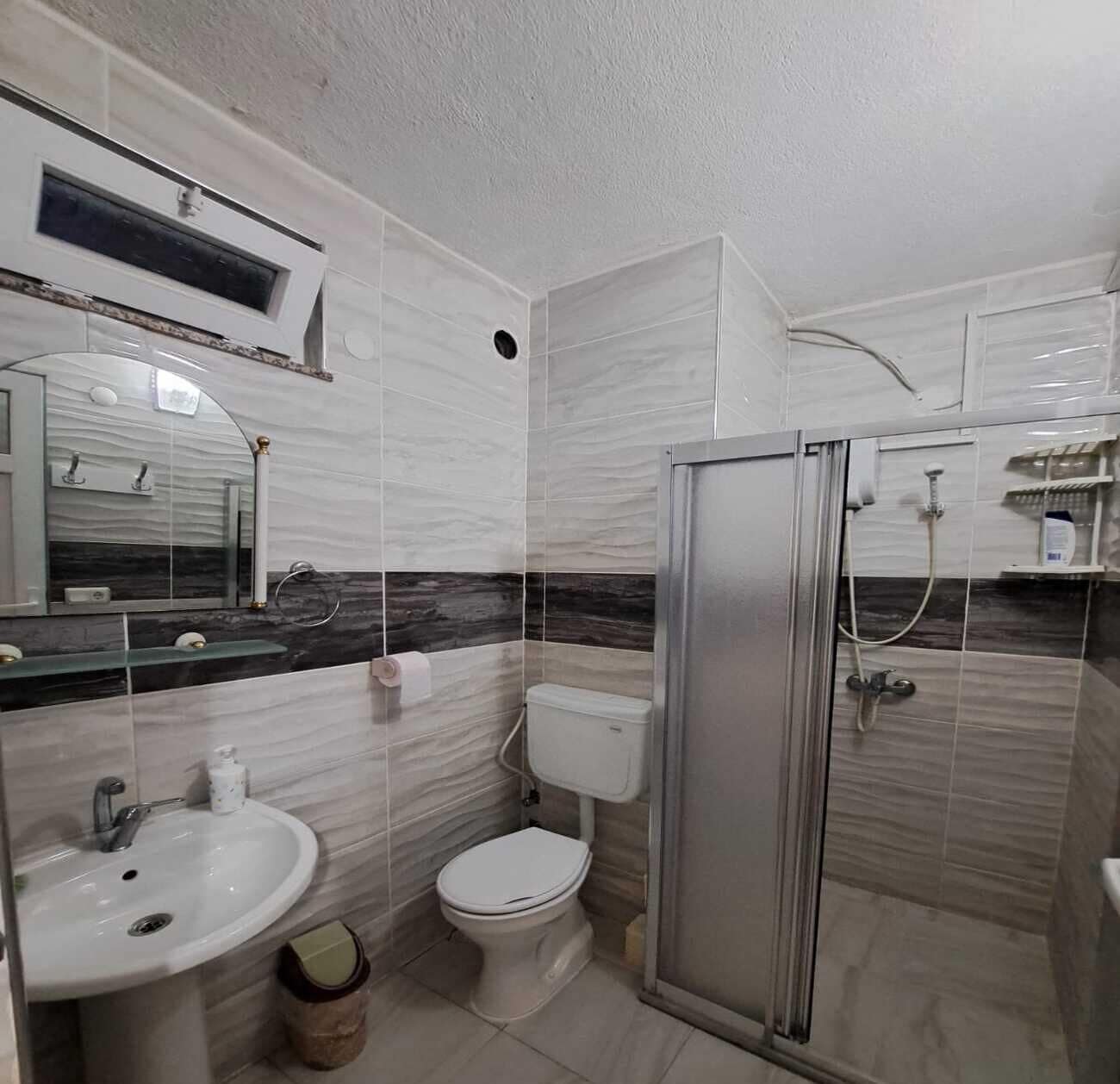A modern bathroom with a toilet, sink, and shower.