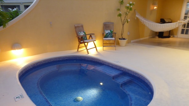 A swimming pool with a tiled edge, a hammock, and two chairs. - 2 Westlook (Gibbes)