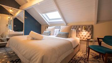 Ein Schlafzimmer mit einem großen Bett, einem Oberlicht, einem Spiegel und einem kleinen Tisch mit einer Lampe.