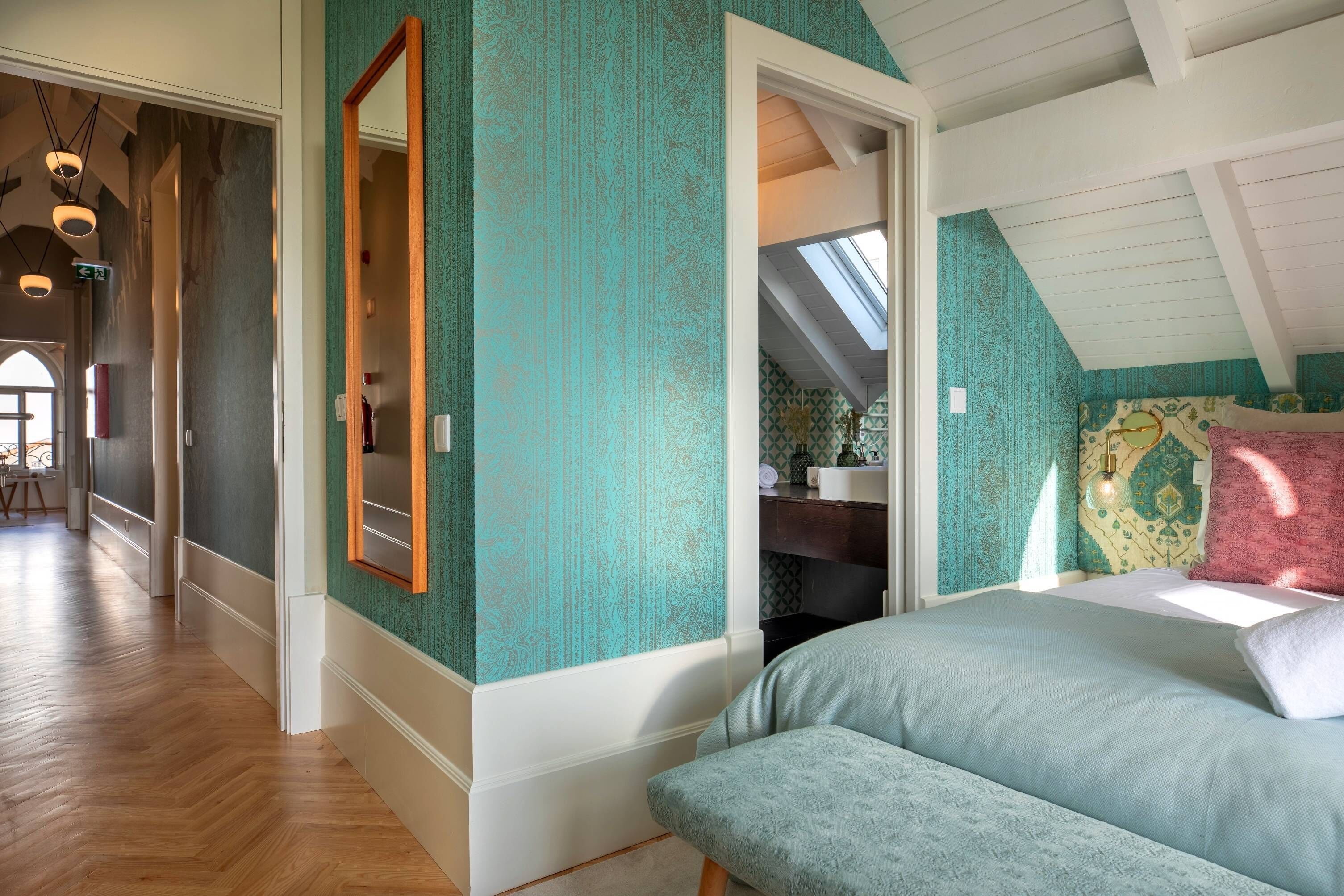 Une chambre avec un plafond en pente, un grand lit, une commode et un miroir.