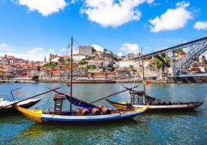 A harbor with traditional boats, a bridge, and historic buildings in the background.