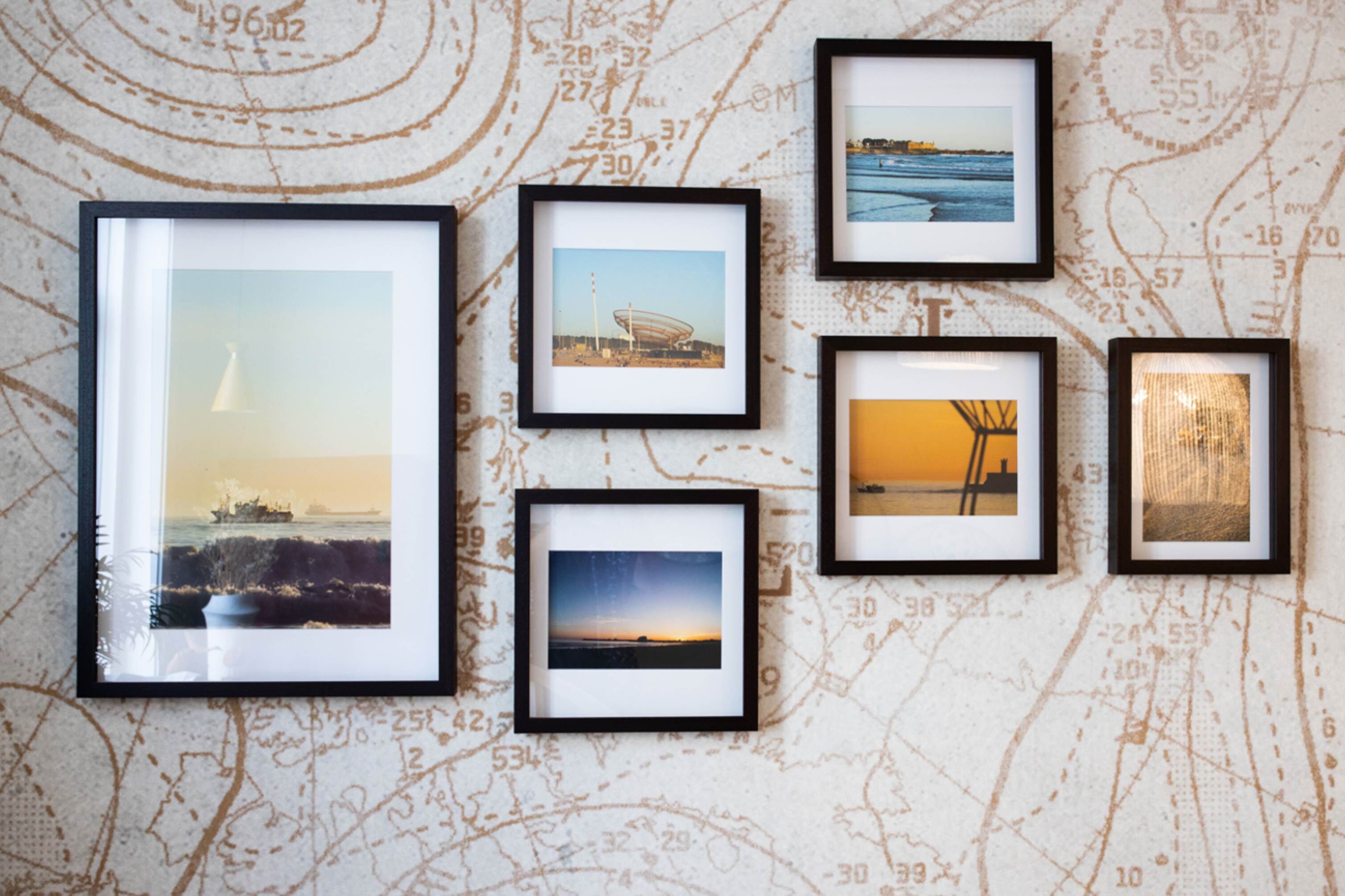 A wall with six framed photographs of various landscapes and structures.