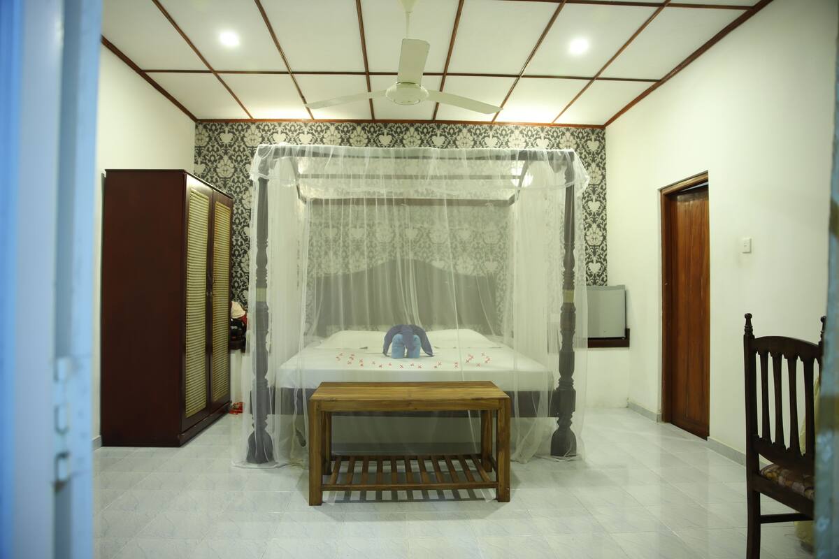Un dormitorio con cama a dosel, un banco de madera, un armario y un ventilador de techo.