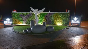 A landscaped entrance area with a decorative statue, a sign indicating 'Regal Residency Entrance', and a sign for 'Regal Residency Exit Only'. - Regal Residency (Auckland)