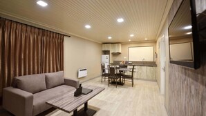 A compact living space with a sofa, a dining table, and a kitchenette. - Regal Residency (Auckland)