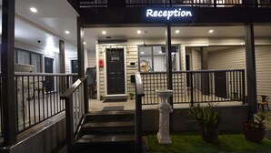 A reception area with a sign, a staircase, and a small garden with potted plants. - Regal Residency (Auckland)