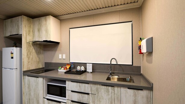 A modern kitchen with a built-in oven, a stainless steel sink, and a microwave. - Regal Residency (Auckland)
