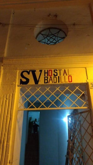 Une enseigne indiquant « SV Hostal Badillo », avec une fenêtre et une porte.
