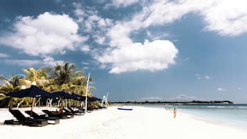 Praia particular, areia branca, espreguiçadeiras, guarda-sóis