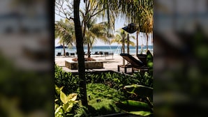 Una veranda fronte spiaggia con poltrone relax, un pontile in legno e vista sull'oceano.