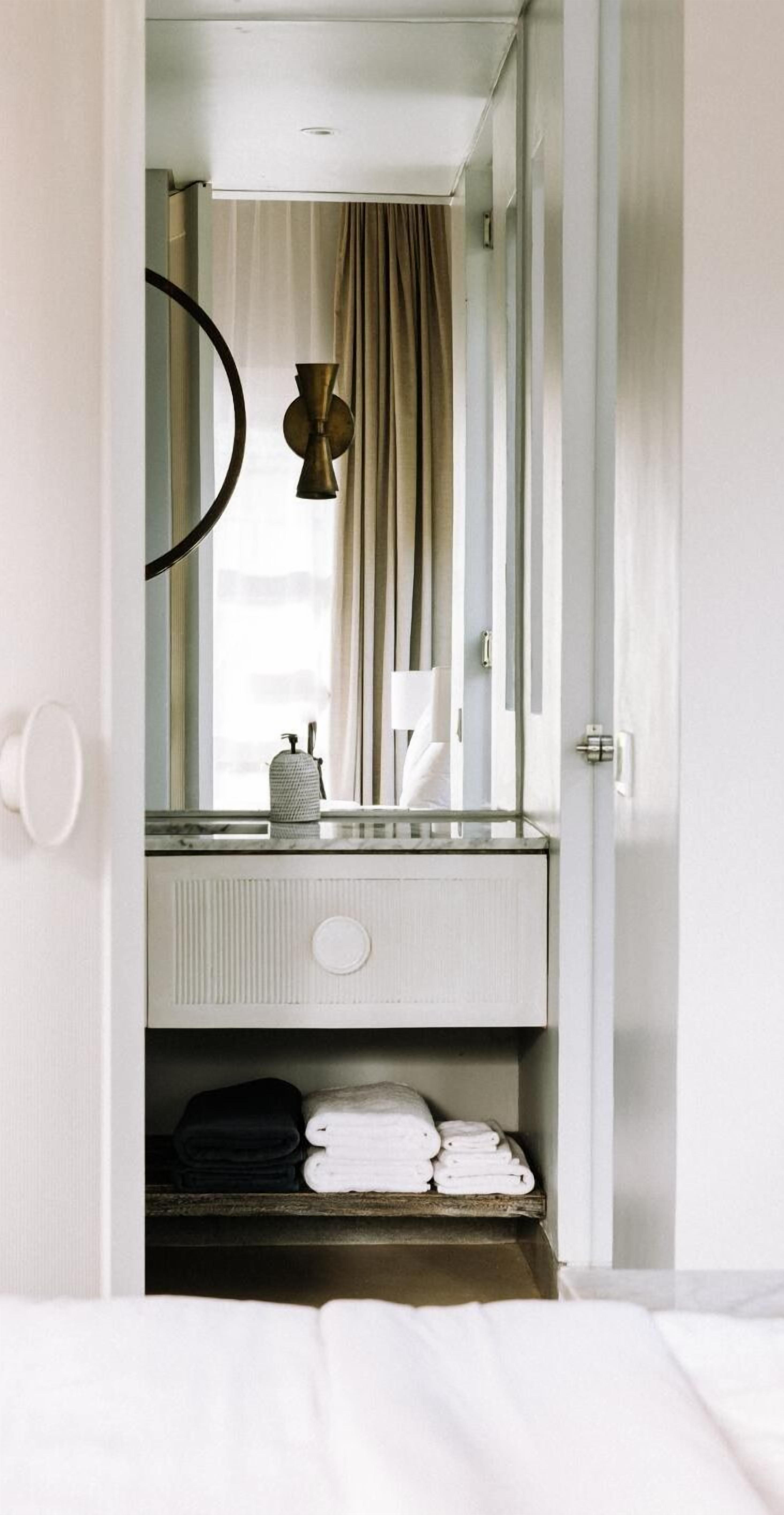Une chambre d’hôtel avec un grand miroir, un porte-serviettes et un lit.