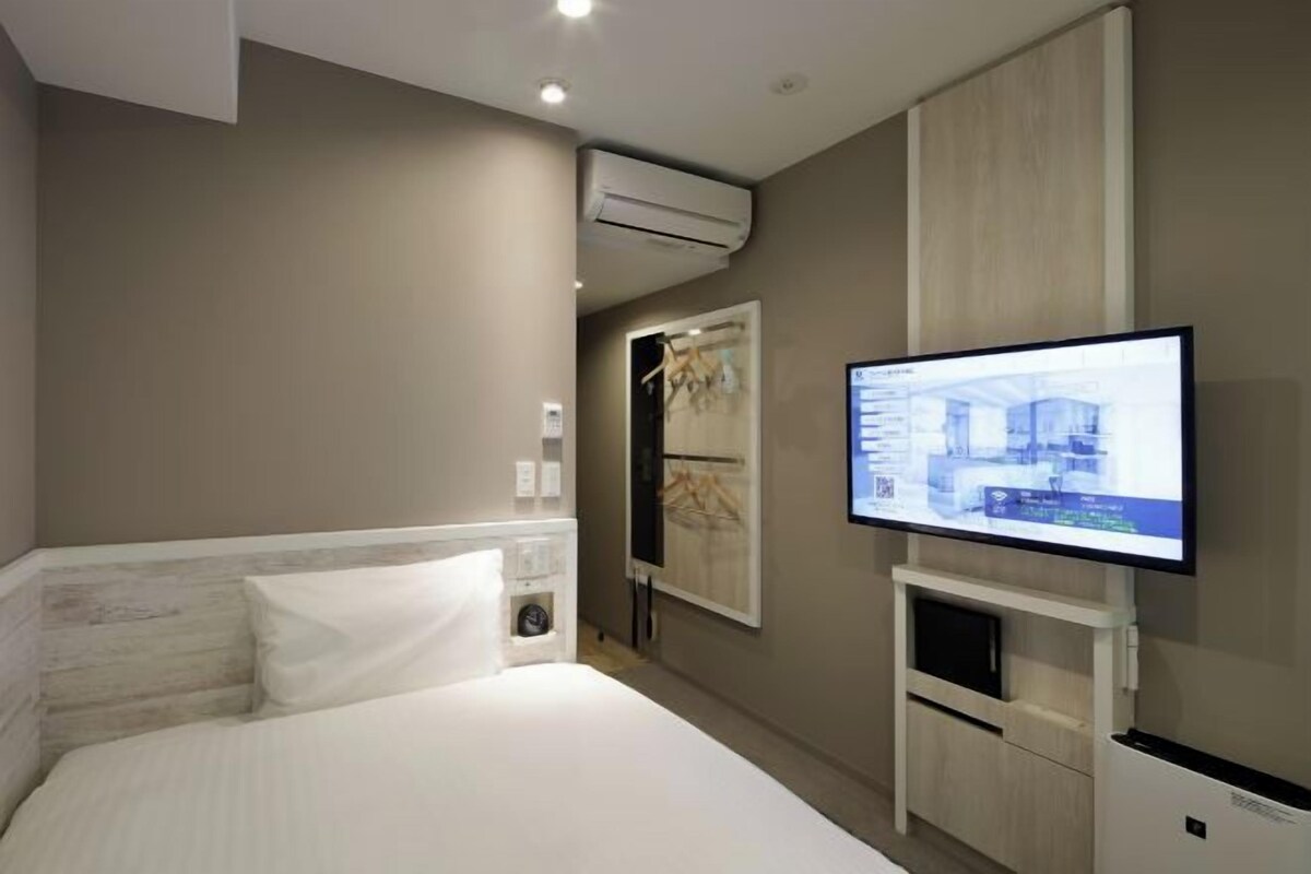 Une chambre d’hôtel équipée d’un lit, d’un téléviseur fixé au mur, d’un système de climatisation et d’une armoire.