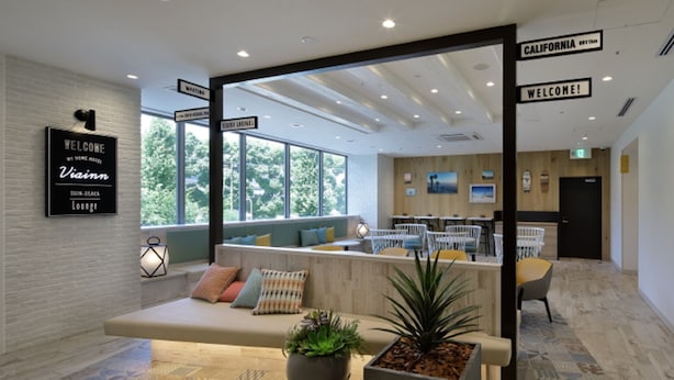 Een moderne zithoek met een bank, stoelen en potplanten.