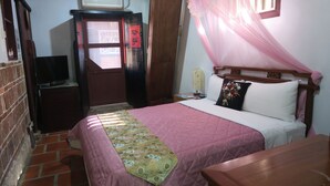 A bedroom with a bed, a bedside table, a TV, a wardrobe, and a window with a curtain. - Shuitou Inn I (Jincheng)