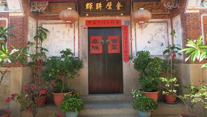 A traditional Chinese building with a wooden door, red banners, and potted plants. - Shuitou Inn I (Jincheng)